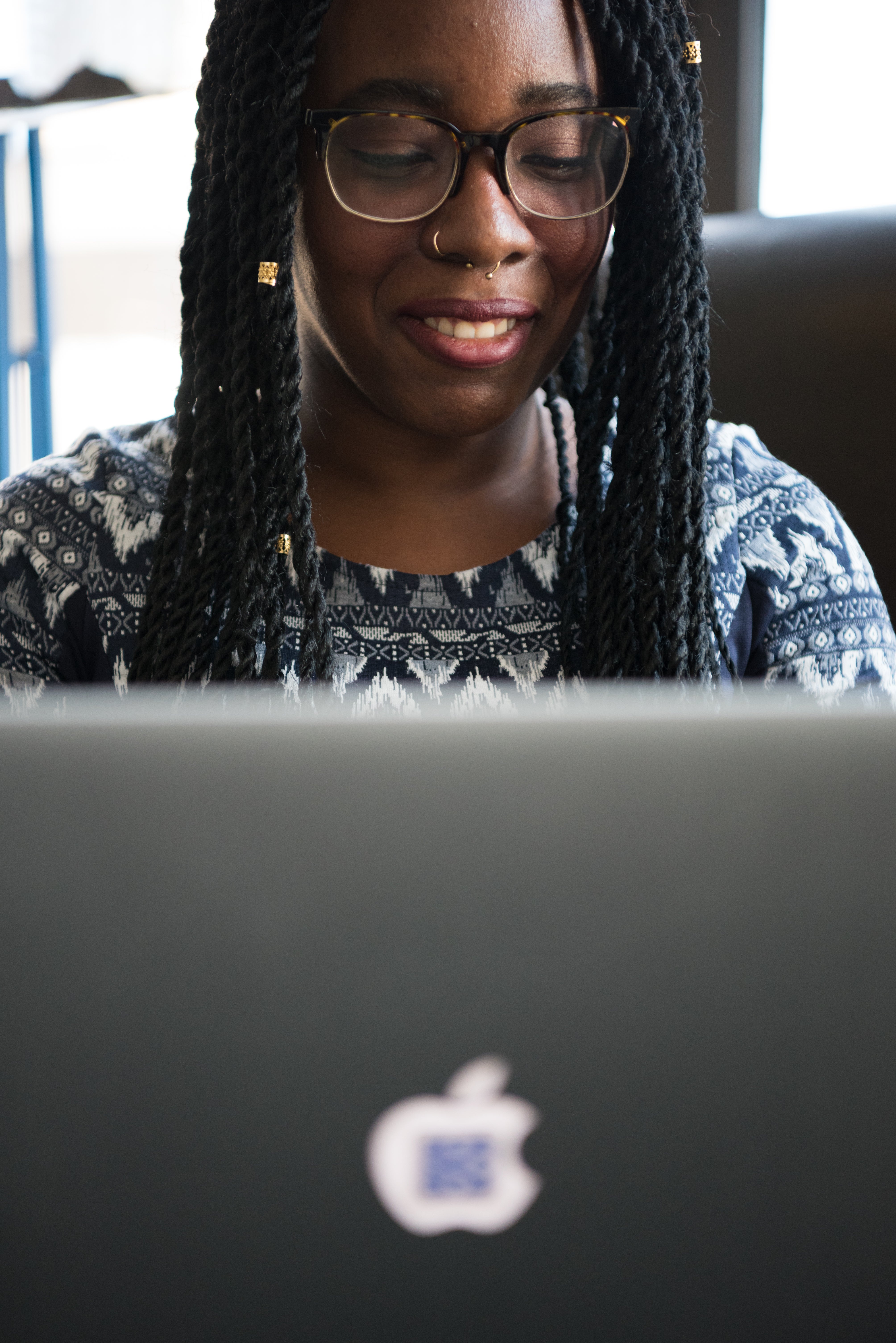 A Black woman in technology smiling while working on her laptop